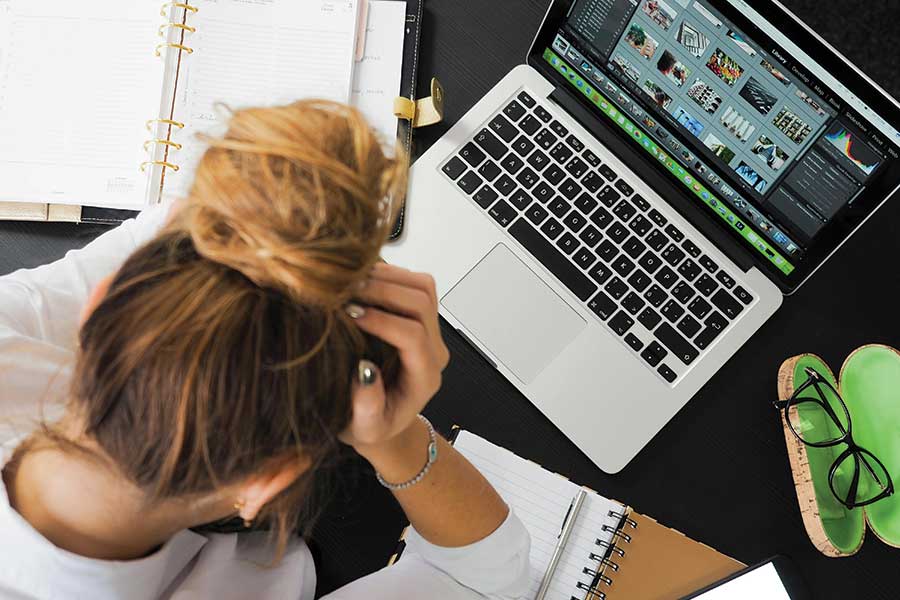 image of a woman at her desk with her head in her hands after her computer freezes. Photo by energepic.com: https://www.pexels.com/photo/woman-sitting-in-front-of-macbook-313690/