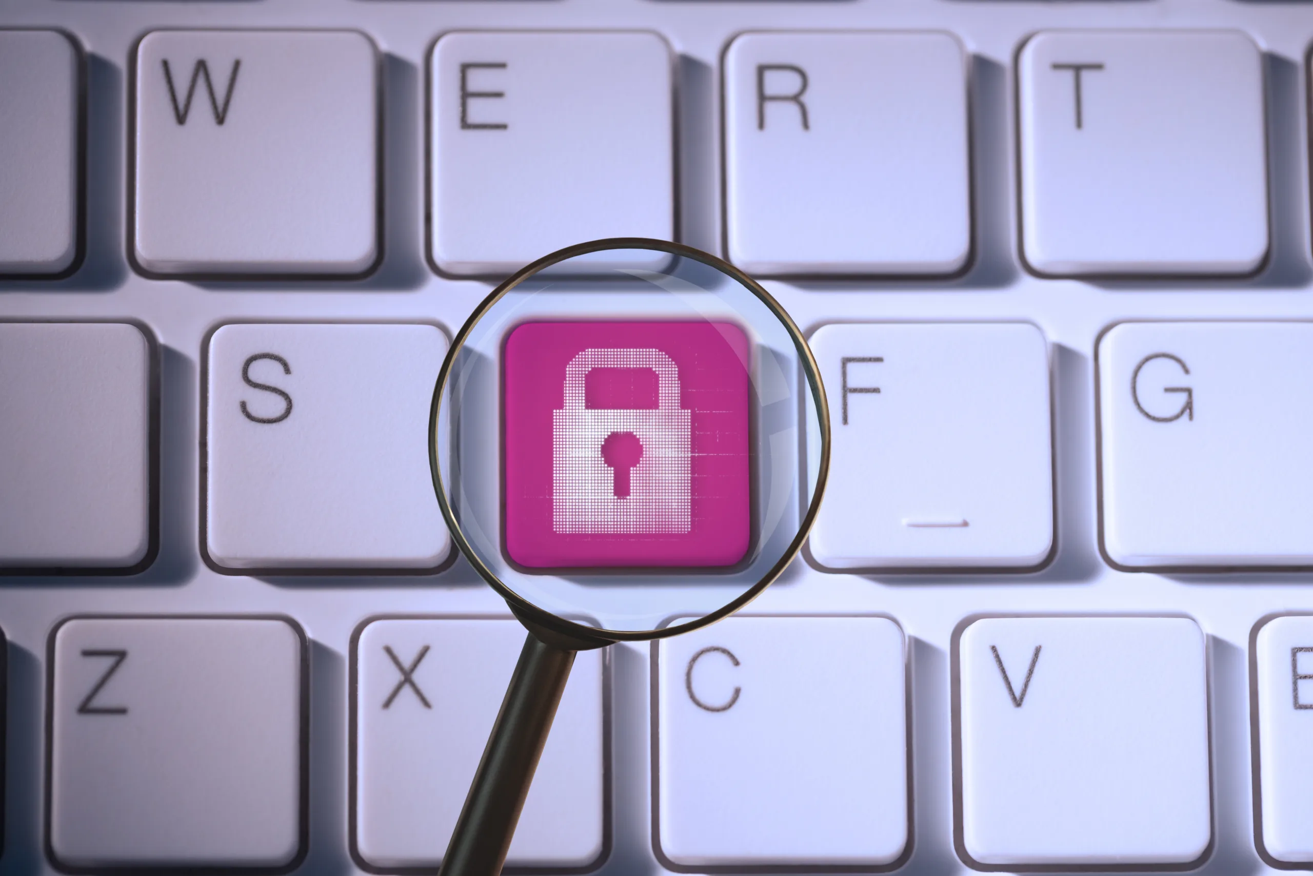 Magnifying glass highlighting a lock icon on a keyboard, representing privacy compliance and data protection.