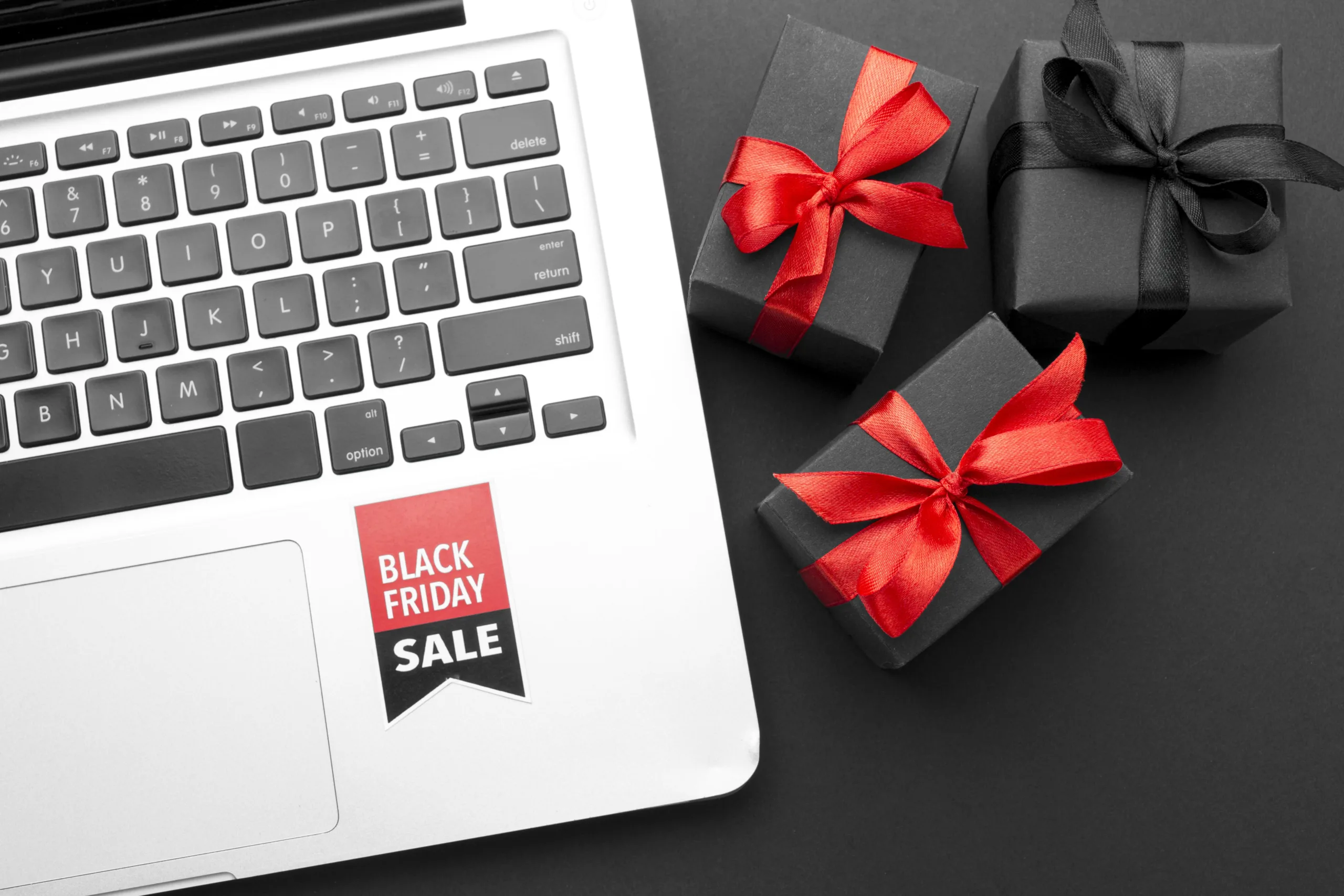 Laptop with a Black Friday sale sticker and gift boxes, representing tech deals that can boost business productivity.