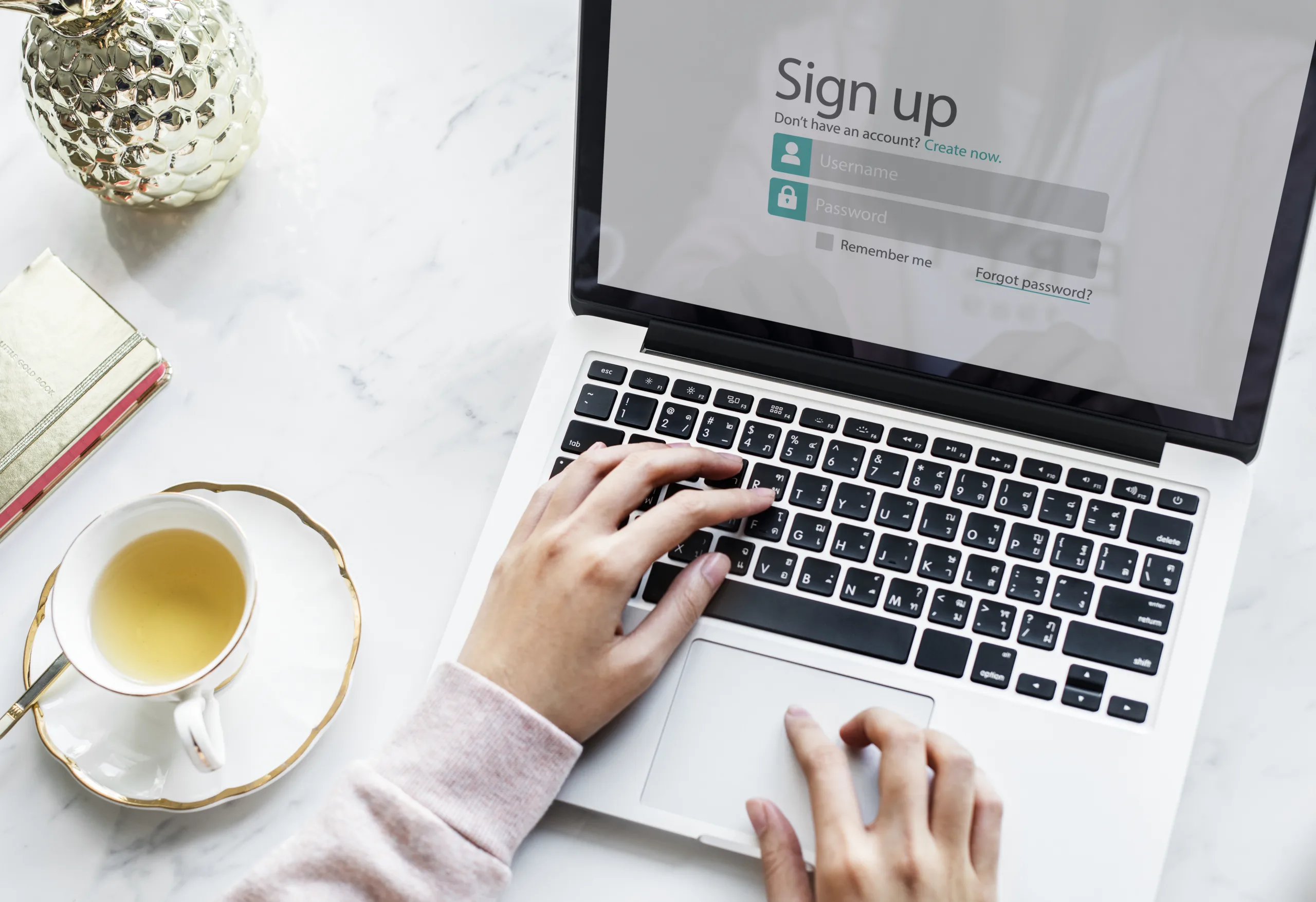 A person typing on a laptop keyboard with a generic login and sign-up screen visible, demonstrating how a user might interact with a fraudulent phishing site.