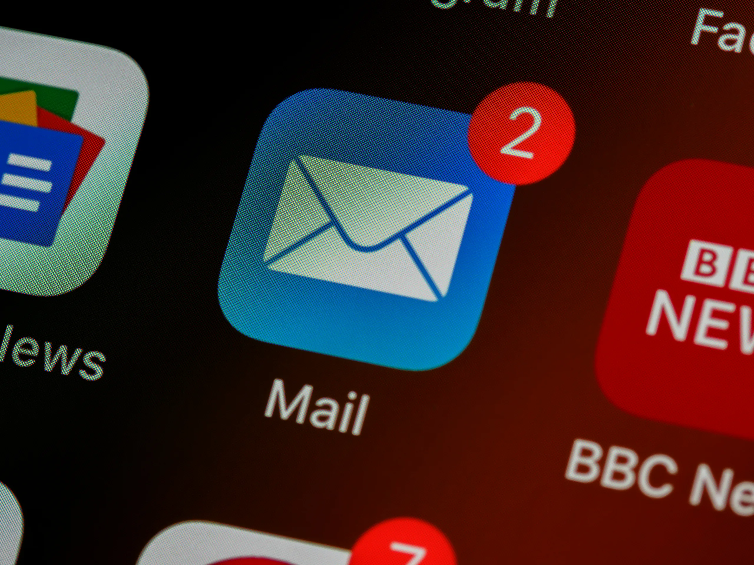 Close-up of a smartphone screen showing a blue Mail app icon with a white envelope and a red notification badge indicating two unread messages.