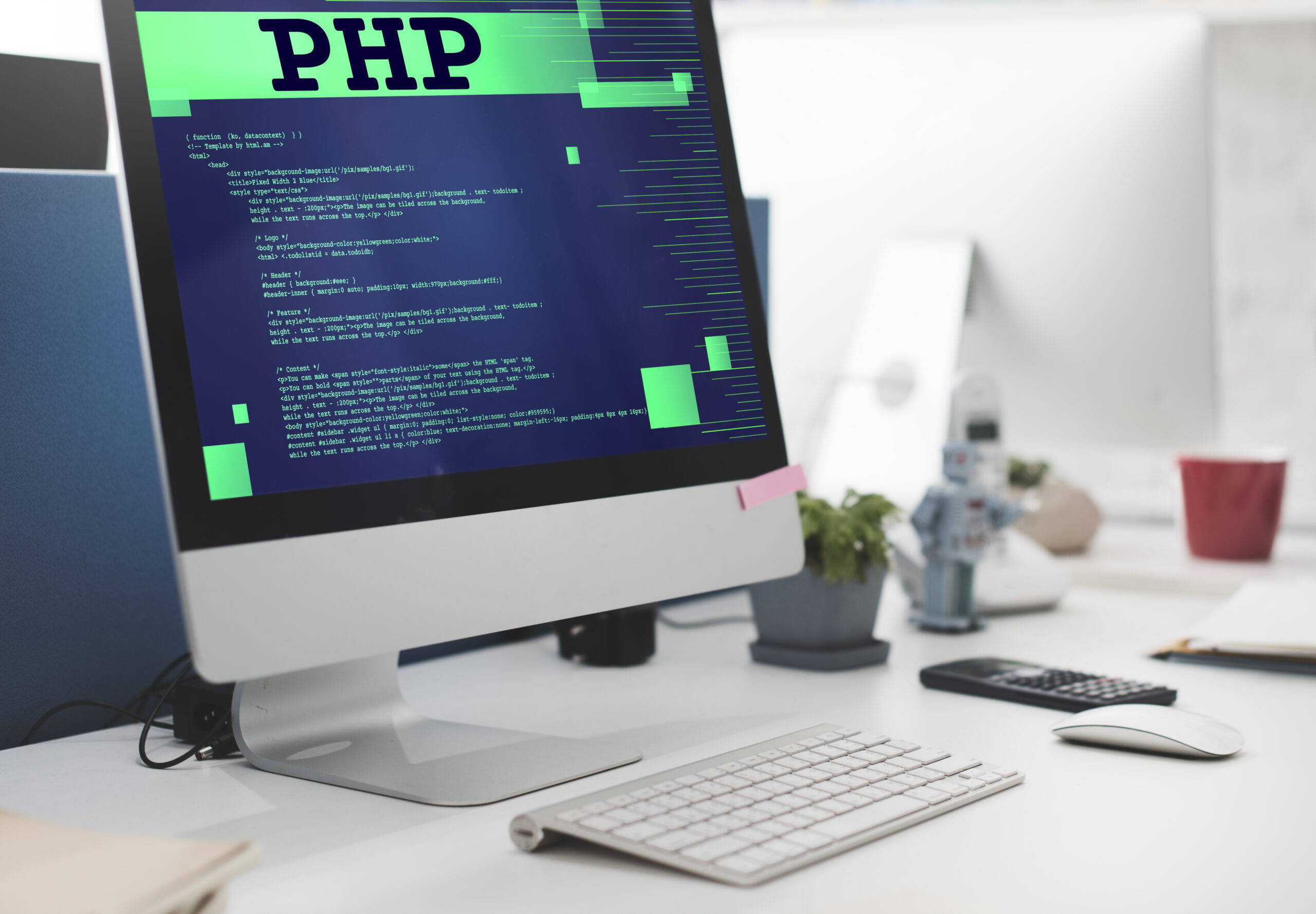 A desktop computer monitor displaying green programming code and a large PHP header on a white office desk.
